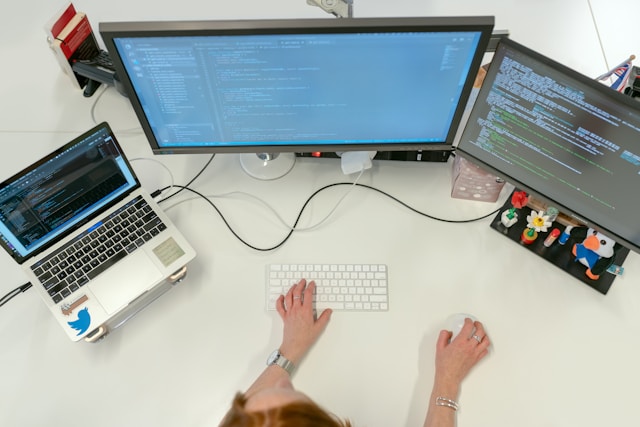 Engenheira de software codificando em sua mesa com vários monitores